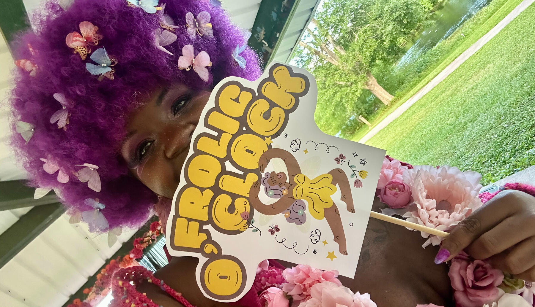 Fae host holding frolic o clock sign.