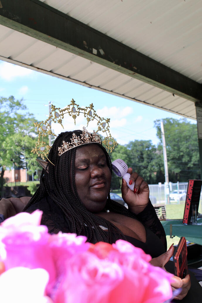 Candid shot of dark fae royalty holding a mini hand fan with bouquet of roses in the frame's front.